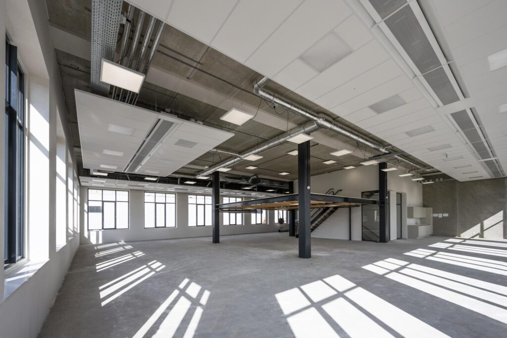 Spacious industrial-style interior at Paul van Vlissingenstraat with large windows, exposed ceilings, and a mezzanine floor.